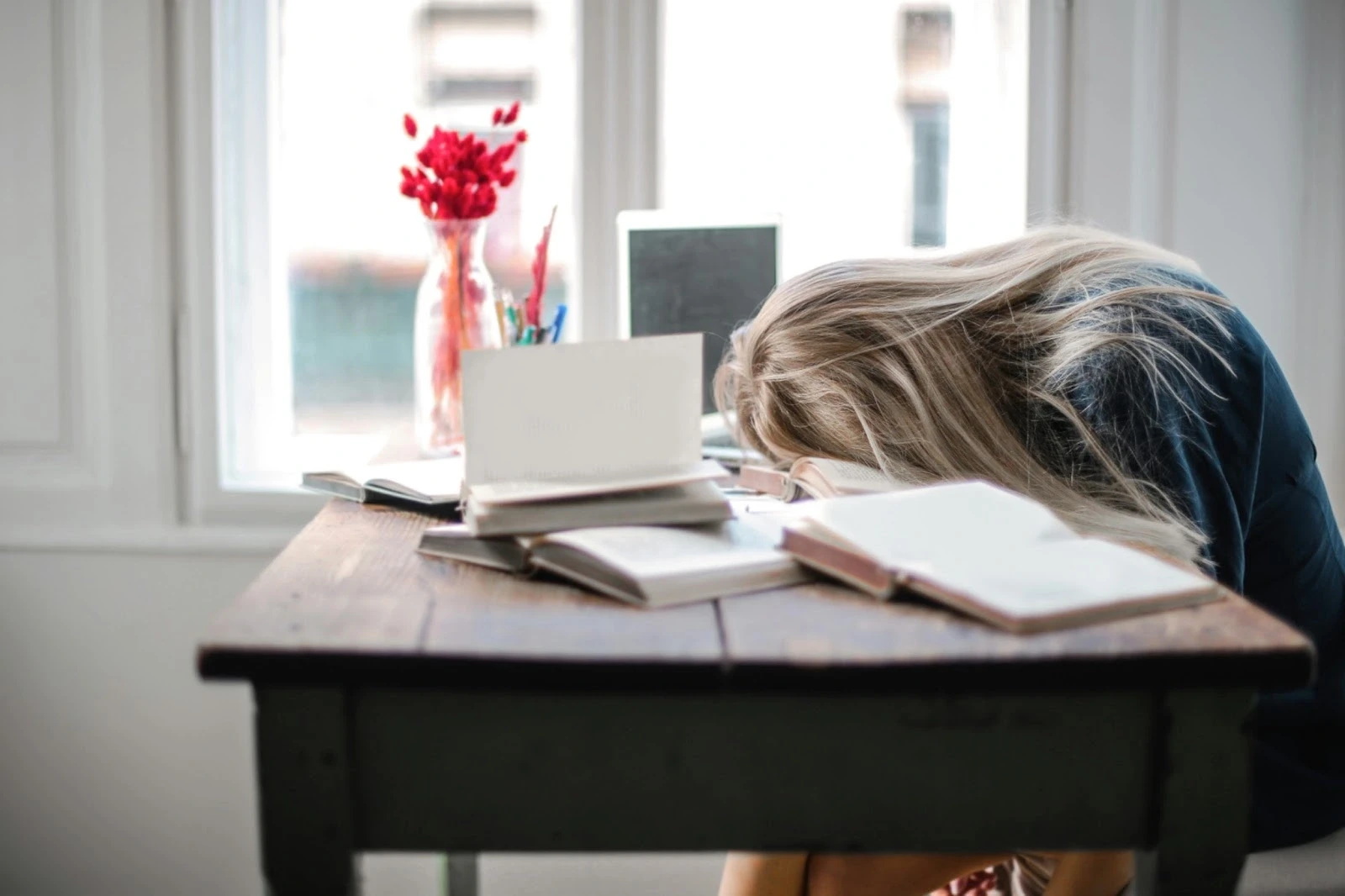 Student leaning on a desk with notebooks and books for studying
