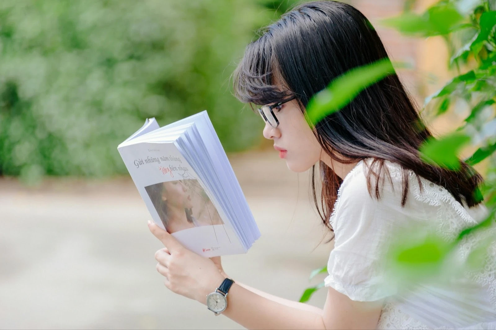 Joven estudiante concentrada leyendo un libro al aire libre